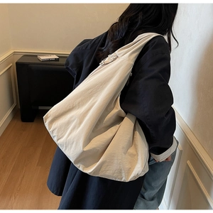Detailed back view of a person wearing a large off-white nylon crescent tote bag