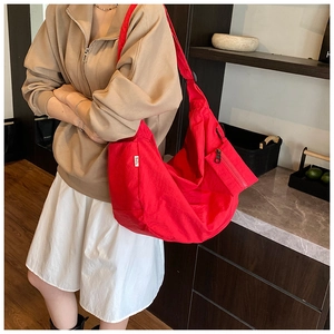 Detail of red nylon crossbody bag with pleated design and adjustable shoulder strap