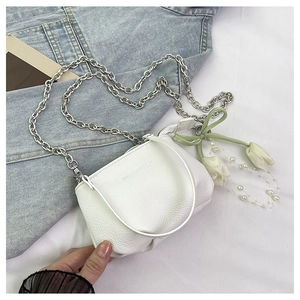 Détail du sac seau en cuir grainé blanc avec chaîne argentée et ruban floral décoratif