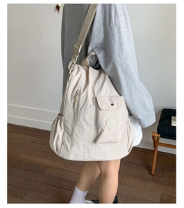 Detail of off-white nylon backpack with buckle flap and side pockets on model