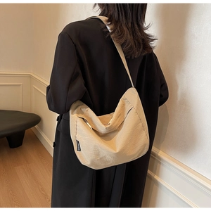 Detail of minimalist beige pleated crossbody bag with metal zipper and adjustable strap