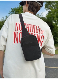 Vista trasera de una mochila de pecho casual de nailon negro sobre una camiseta blanca oversize
