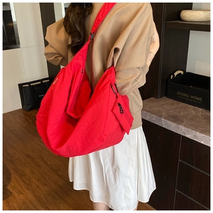 Close-up of a large red nylon crossbody bag with a matching mini pouch and carabiner