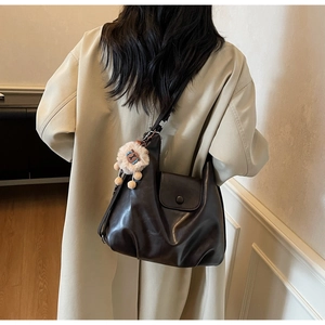 Dettaglio della borsa hobo in pelle opaca marrone scuro con un simpatico ciondolo leone
