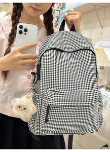 Détail d'un sac à dos à carreaux avec pendentif étoile en peluche et bretelles