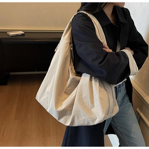 Detailed shot of beige large capacity canvas tote bag worn over the shoulder for commute