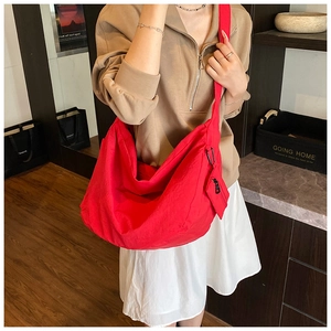 Detailed view of red hobo bag with wide shoulder strap and matching mini pouch pendant