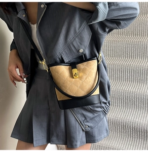 Détail d'un sac seau matelassé avec fermoir rotatif métallique et finitions dorées chic