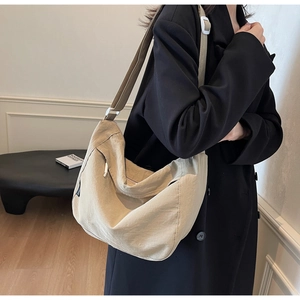 Close-up of beige pleated nylon crossbody bag showing texture and adjustable strap