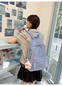 Détail d'un sac à dos en toile vichy bleu et blanc avec pendentif étoile en peluche rose