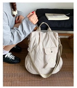 Detail of a beige multi-functional travel backpack featuring wrinkled nylon and a round logo