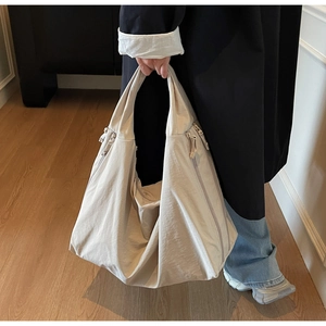 Detail view of large canvas tote bag showing side zipper pocket and texture