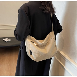 Detail view of khaki pleated crossbody bag with side woven label and minimalist design
