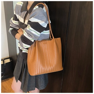 Detail of caramel brown woven leather tote showing rich texture and braided shoulder strap
