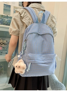 Vue détaillée d'un sac à dos à carreaux bleus et blancs avec un charm étoile en peluche