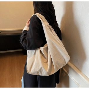 Detailed view of the wide shoulder strap and textured fabric on the beige tote bag