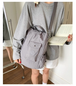 Detailed view of gray nylon travel bag featuring front flap pocket and adjustable strap