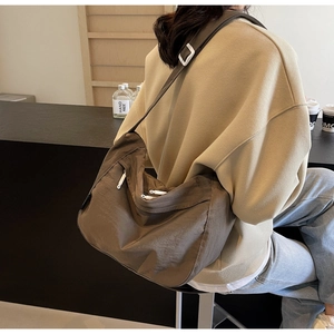 Detailed back view of a dark khaki nylon pleated crossbody bag with white hardware