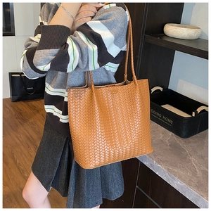 Detail shot of a brown woven leather tote bag featuring a classic checkered texture and straps