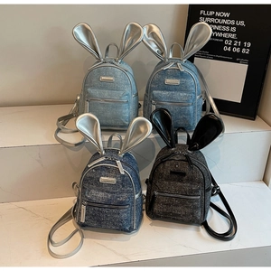 Macro detail of sparkly denim mini backpacks with cute rabbit ears and metal logo
