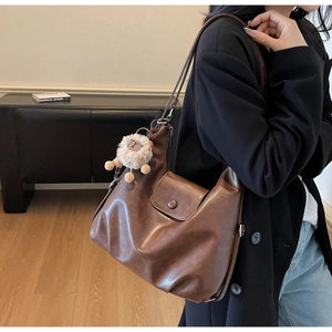 Dettaglio di una grande borsa tote marrone scuro in pelle con un ciondolo a forma di pecora