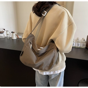 Detail of dark brown nylon pleated crossbody bag showing large capacity and adjustable strap
