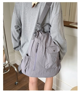Detail of grey nylon backpack featuring side pockets and adjustable wide fabric strap