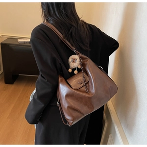 Dettaglio della grande borsa tote retrò marrone scuro con ciondolo alpaca su una modella