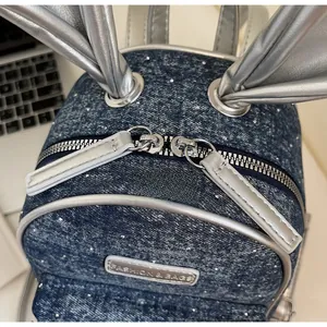 Detail view of mini blue denim backpack with silver rabbit ears and double zippers