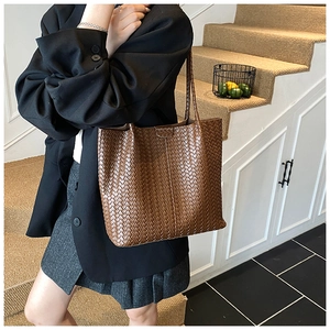 Close-up of vintage brown woven tote bag with intricate leather texture and shoulder strap