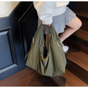 Detail of olive green nylon tote bag showing waterproof texture and side metal zipper