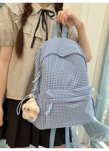 Détail du sac à dos à carreaux bleus et blancs avec peluche sur un mannequin femme