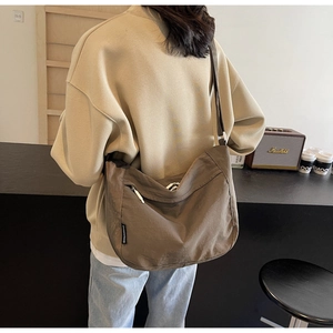 Detailed view of the earth-tone pleated crossbody bag with white side zipper pocket