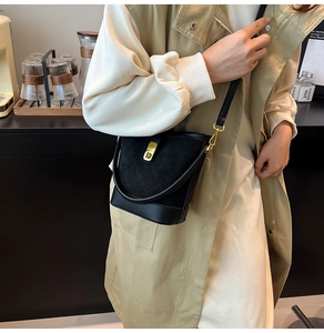 Sac seau matelassé noir avec fermoir doré porté dans un café pour un look élégant