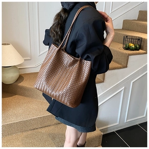 Detailed view of brown woven leather tote bag texture on female model in street style
