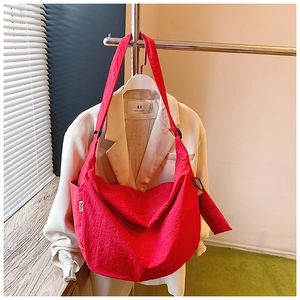 Macro view of a red nylon shoulder bag with a small matching purse and wide strap