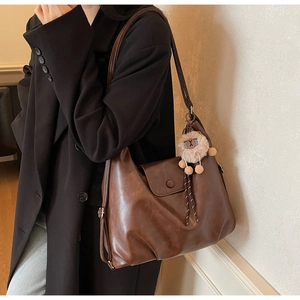 Dettaglio della grande borsa tote marrone vintage con un simpatico ciondolo ad alpaca