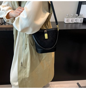 Détail du sac seau matelassé noir en cuir mat et lisse avec fermoir doré brillant