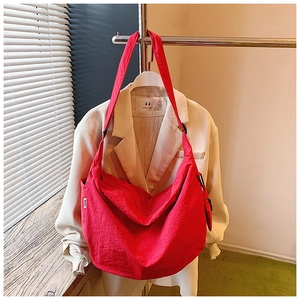 Detail of red nylon crescent bag hanging on a hanger with adjustable shoulder strap