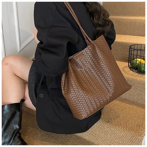 Detailed view of brown leather woven tote bag with classic rhombus pattern worn by a model