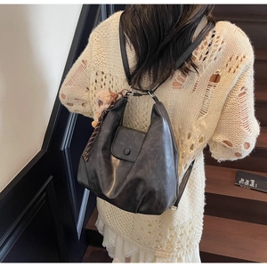 Dettaglio dello zaino vintage in pelle nera con texture morbida e ciondolo di peluche