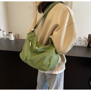 Detail of green pleated crossbody bag showing adjustable strap and large capacity