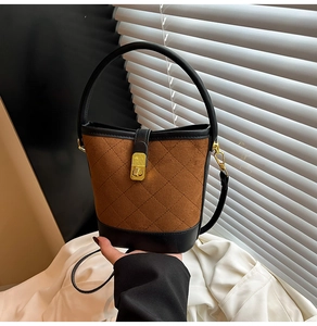 Détail du sac seau matelassé en daim marron avec base noire et fermoir doré rotatif