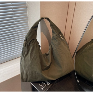 Detail of olive green nylon tote bag with zipper closure and natural wrinkled texture