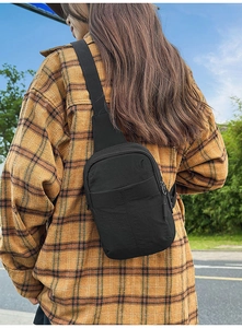 Vista trasera de un modelo con un bolso bandolera negro sobre una camisa de cuadros
