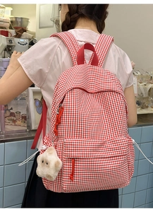 Détail du sac à dos à carreaux rouges et blancs avec poche avant et pendentif étoile