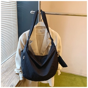 Detail of black nylon crossbody bag with adjustable strap and small coin pouch pendant
