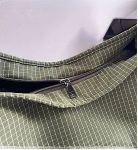 Vue détaillée de la fermeture éclair en métal gris et du tissu à carreaux verts du sac