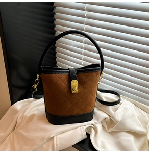 Détail du sac seau en daim marron matelassé avec finitions en cuir noir et fermoir doré