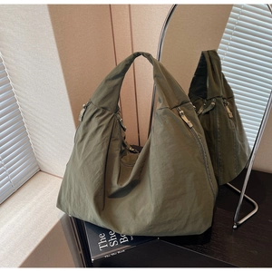 Detail of olive green nylon tote bag featuring side zipper pocket and pleated texture